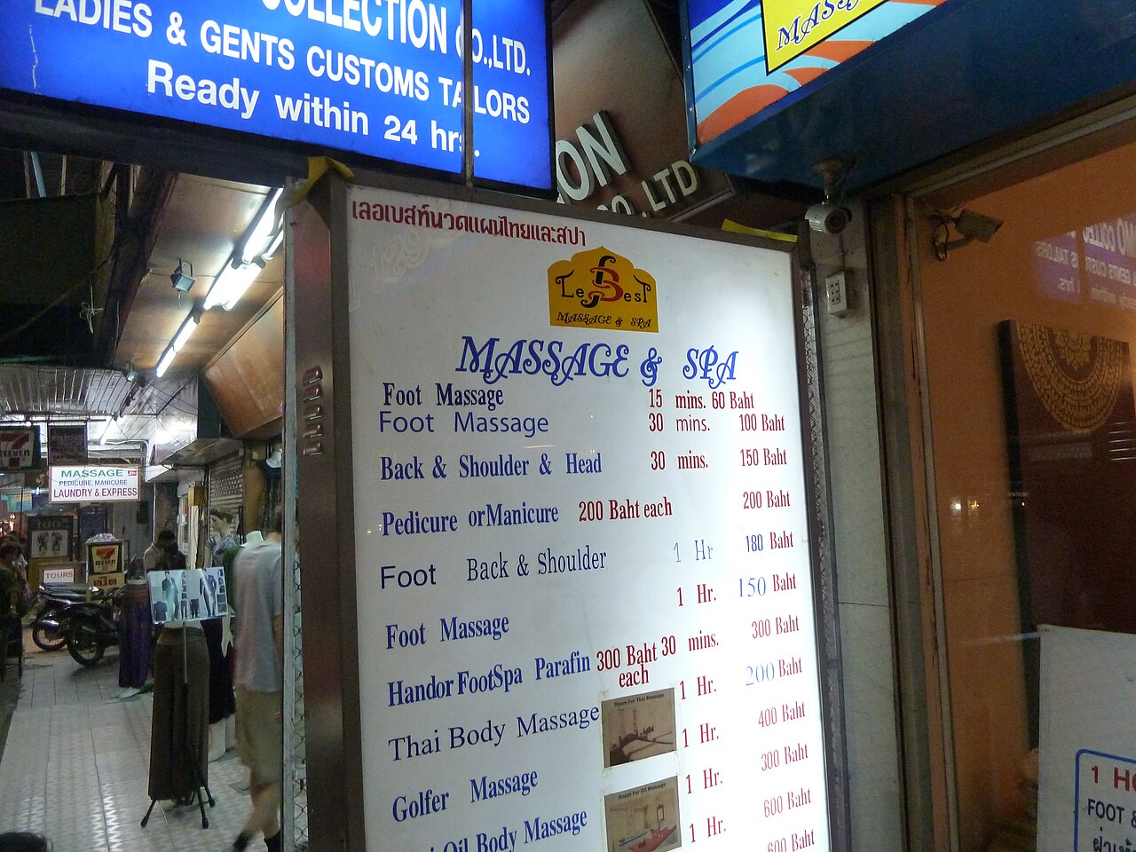 Massage shop price board at Chiang Mai Night Bazaar listing foot massage, Thai body massage and oil massage rates in baht - how Thailand travel costs are posted on the street