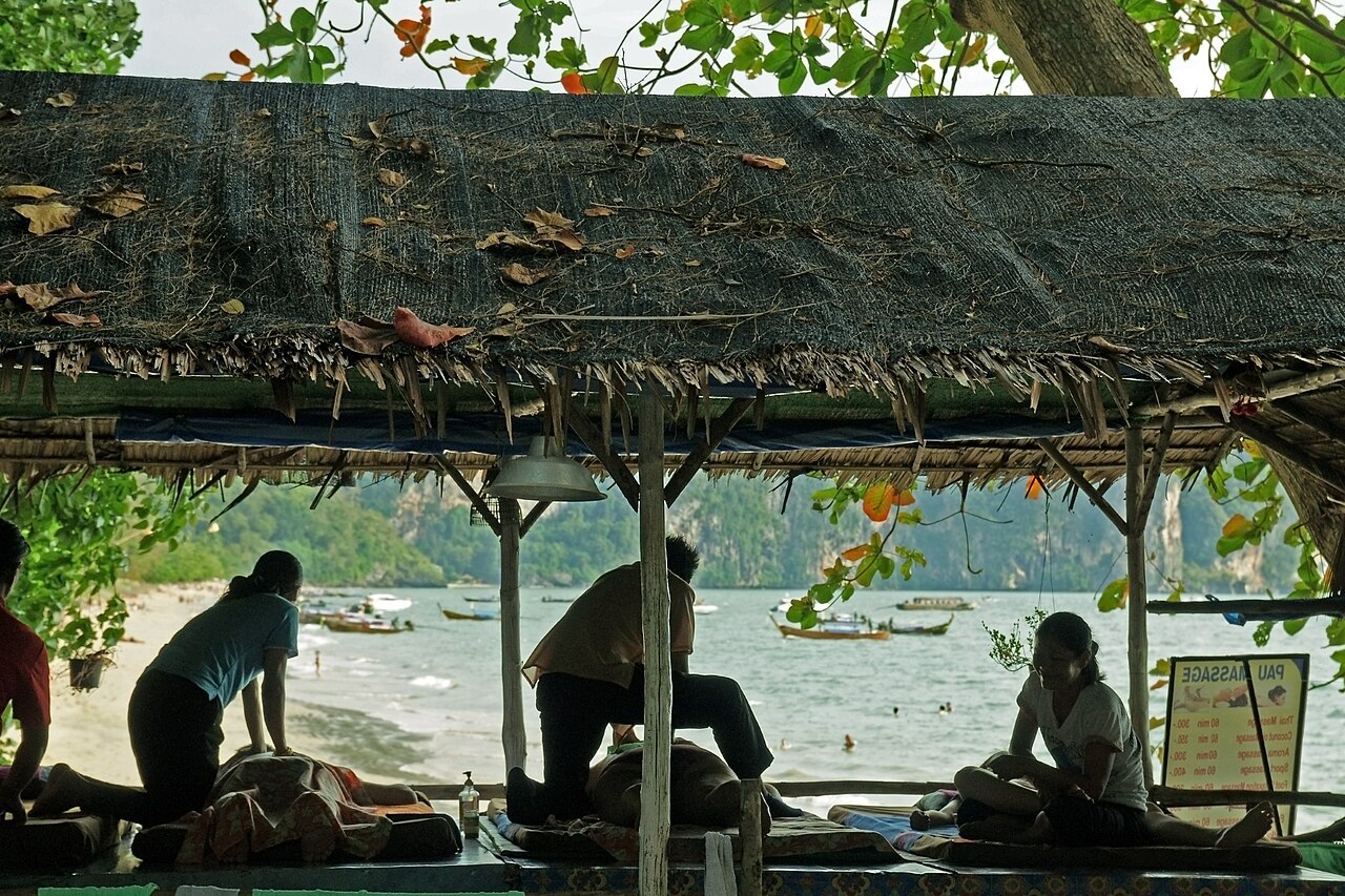 Beach massage sala at Ao Nang, Krabi, with a painted price board showing Thai massage rates in baht - typical Thailand travel costs for an hour of Thai massage