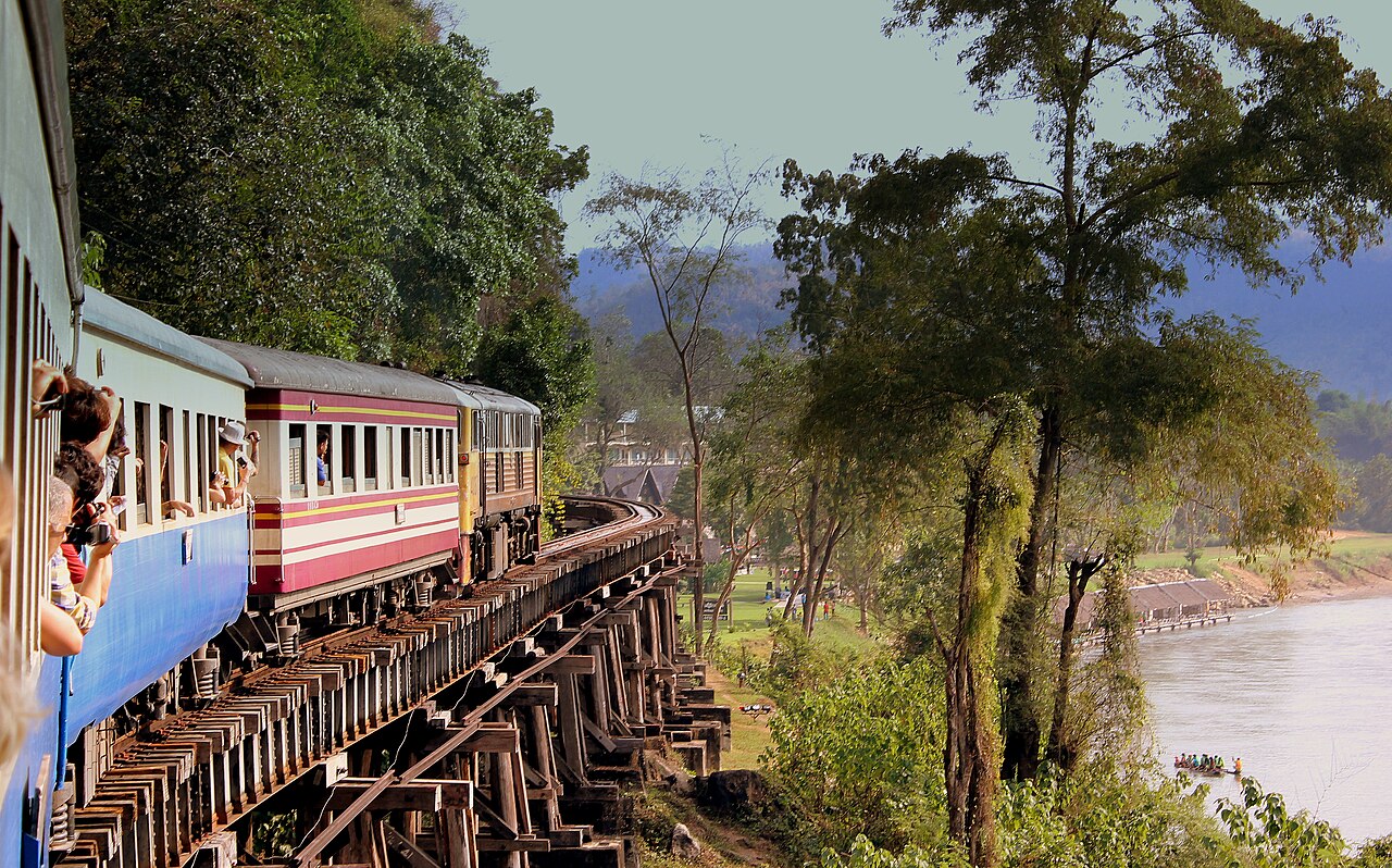 Third-class Thai train crossing the wooden Wampo viaduct beside the River Kwai near Kanchanaburi, the 100 baht Death Railway ride that anchors Thailand budget travel west of Bangkok