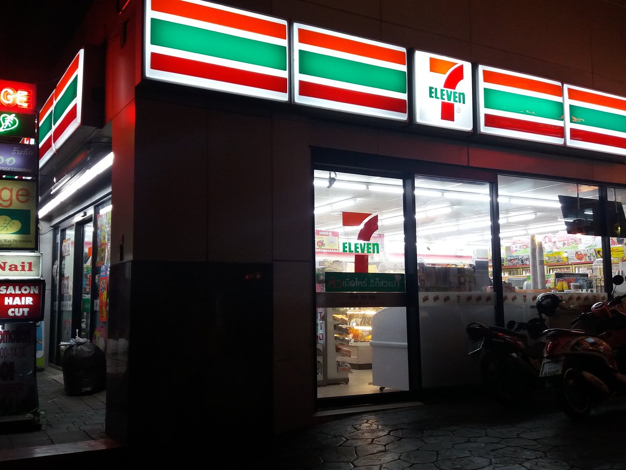 7-Eleven convenience store on Sukhumvit in Bangkok at night, where cheap travel Thailand data top-ups and tourist SIM starter packs are sold from 50 baht