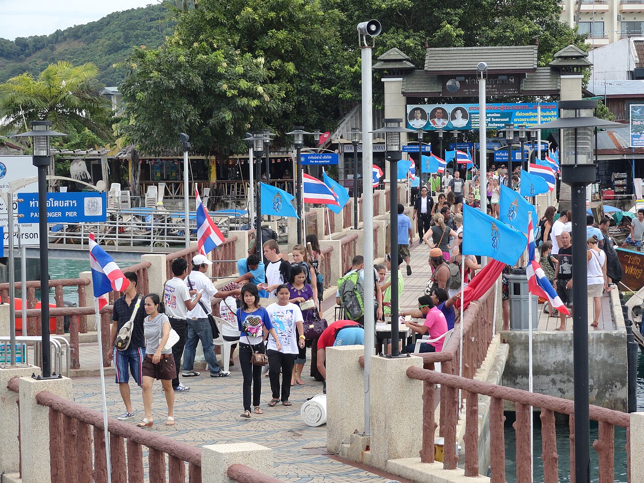 Tourists walking off the passenger ferry at Tonsai Pier on Koh Phi Phi Don, where Thailand budget travel means paying a 20-baht island landing fee in cash before leaving the jetty