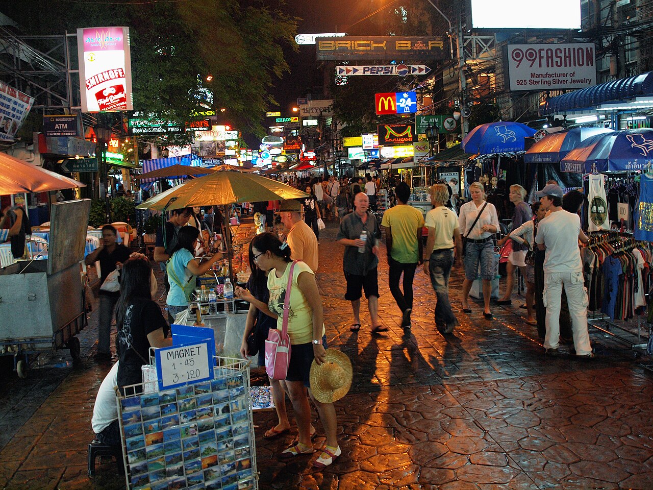 Khao San Road in Bangkok at night with bars, street stalls and crowds, where Thailand travel costs for a 620ml beer run 160 to 220 baht against 65 baht at the 7-Eleven on the same street