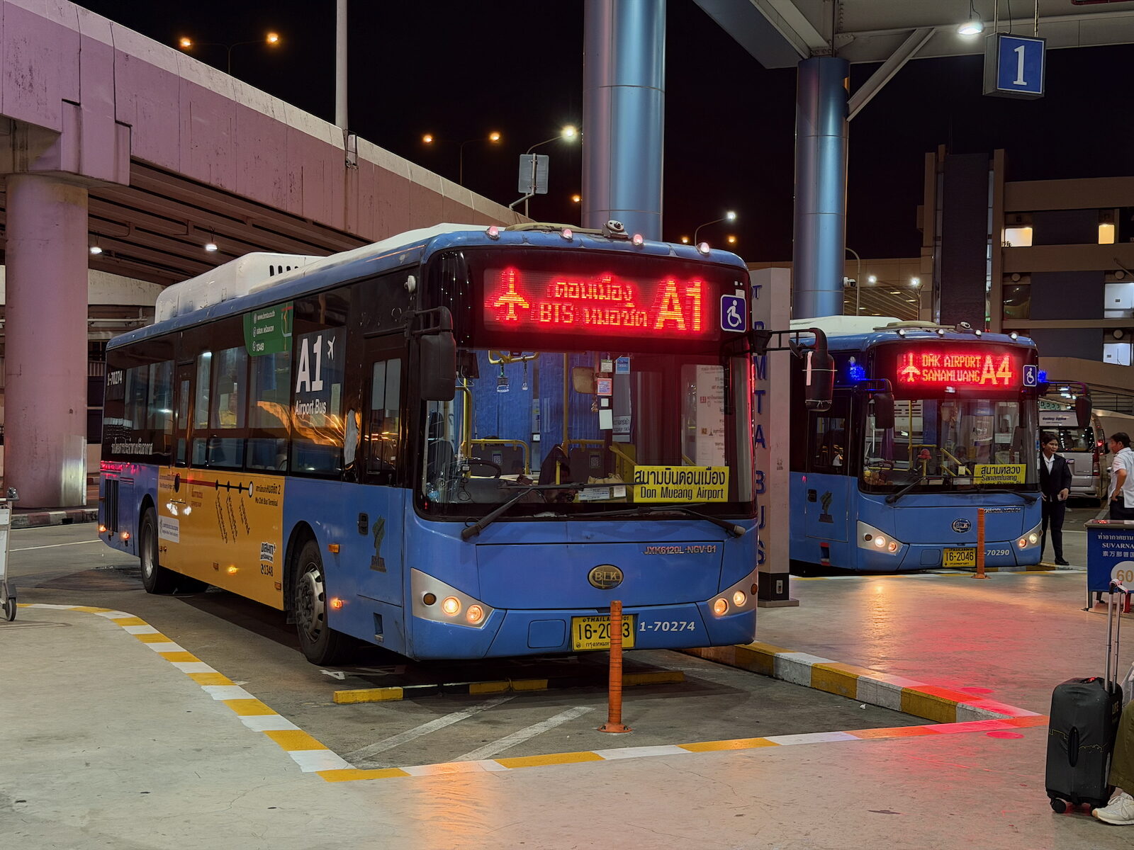 BMTA A1 and A4 airport buses waiting at the Don Mueang airport bus terminal in Bangkok at night, the 30 and 50 baht city routes used in Thailand travel costs comparisons