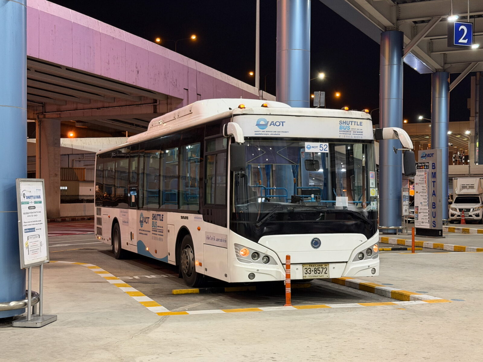 The white AOT inter-airport shuttle bus marked Suvarnabhumi - Don Mueang parked at bay 2 of the Don Mueang airport bus terminal, the free option that cuts Thailand budget travel transfer costs to zero
