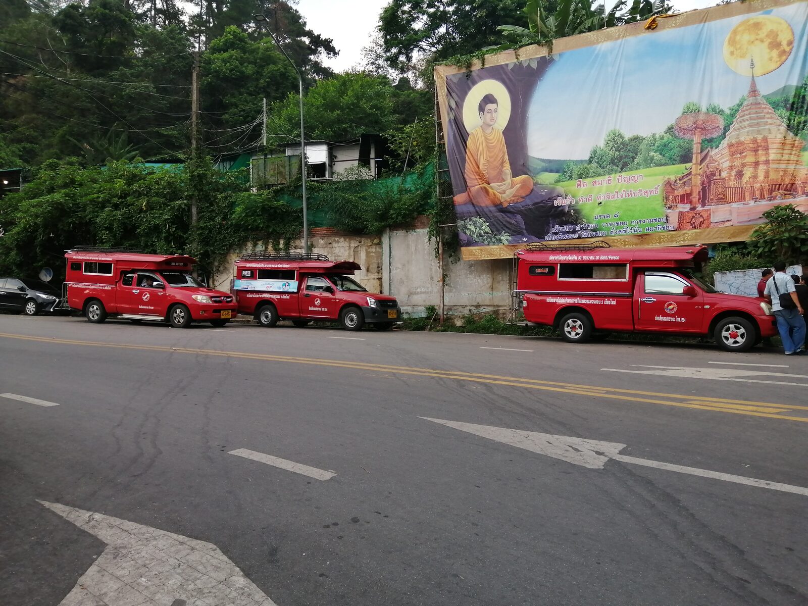 Red songthaews queueing in the car park below Wat Phra That Doi Suthep waiting to fill with passengers for the shared 40 baht ride back down to Chiang Mai