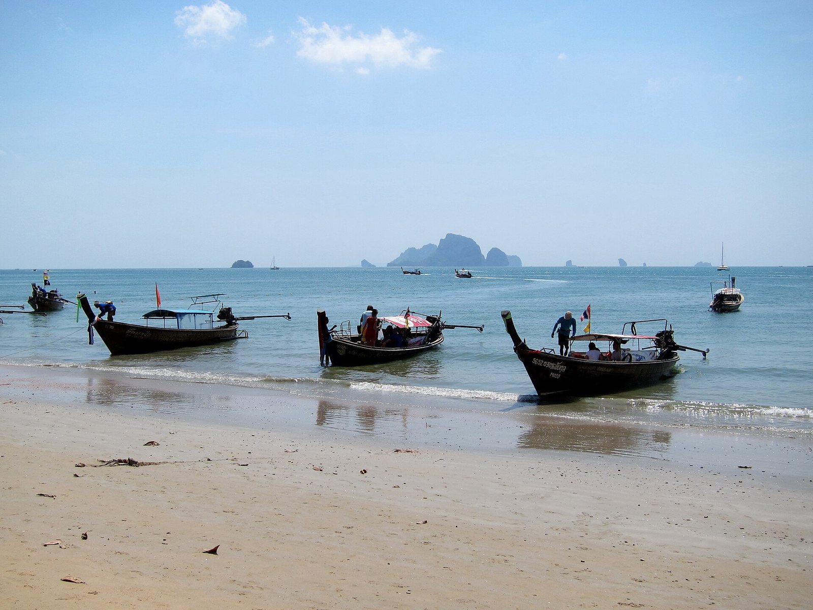Longtail boats loading passengers on Ao Nang beach in Krabi, Thailand, the 100-baht shared crossing to Railay West that sets local Thailand travel costs
