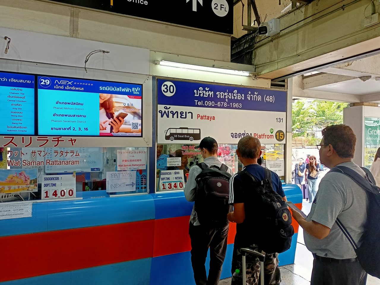 Ticket windows at Ekkamai Eastern Bus Terminal in Bangkok showing destination boards and departure times, where cheap travel Thailand bus fares to Ban Phe and Koh Samet are sold