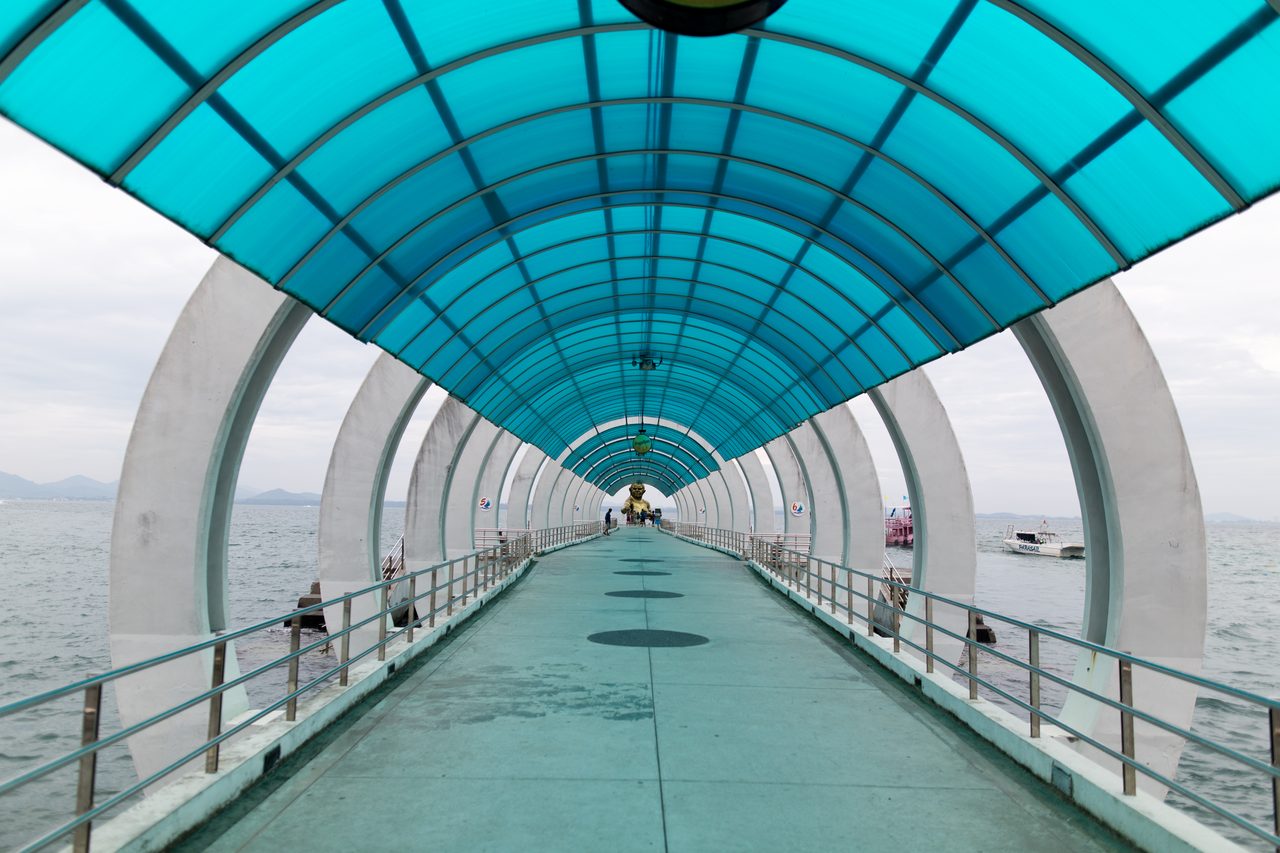 The covered walkway along Ban Phe pier in Rayong with ferries moored alongside, the mainland terminal used for Thailand budget travel from Bangkok to Koh Samet